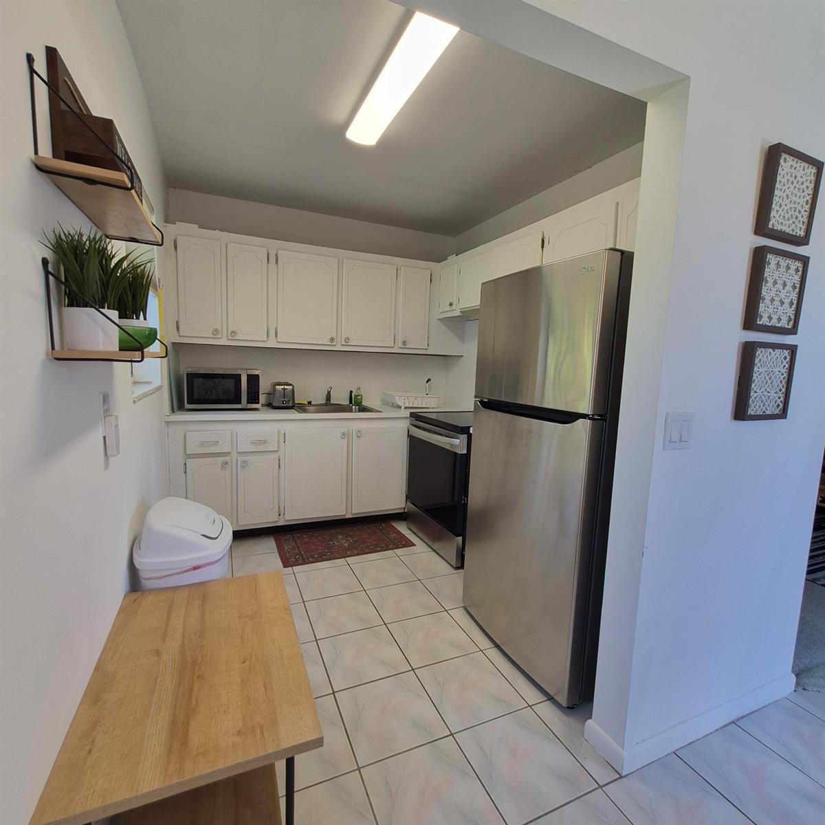 A kitchen with white cabinets, stainless steel appliances, and light-colored tile flooring — 101 Northampton F, West Palm Beach FL 33417, WEST PALM BEACH, FL