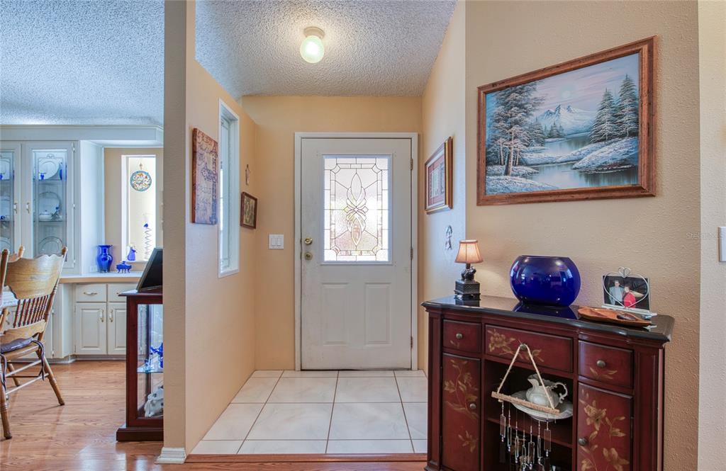 An entryway with a tiled floor, a white front door, and a wooden console table — 258 PELICAN DRIVE N, OLDSMAR, FL