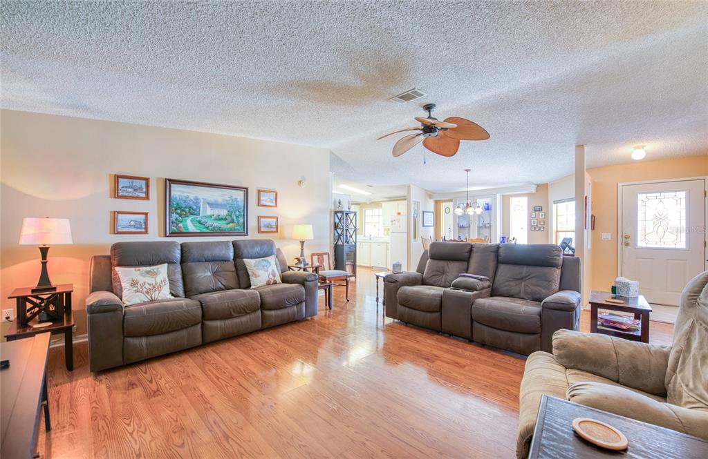 A living room with wood floors, two leather sofas, and a ceiling fan — 258 PELICAN DRIVE N, OLDSMAR, FL
