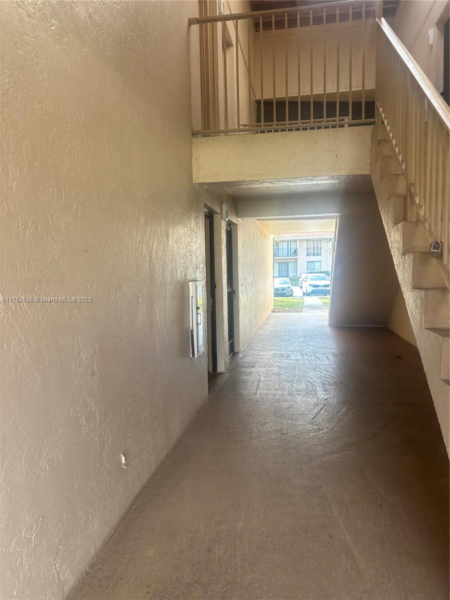 An outdoor covered walkway leads to a staircase and building entrance — 5851 Washington St # 84, Hollywood FL 33121, HOLLYWOOD, FL