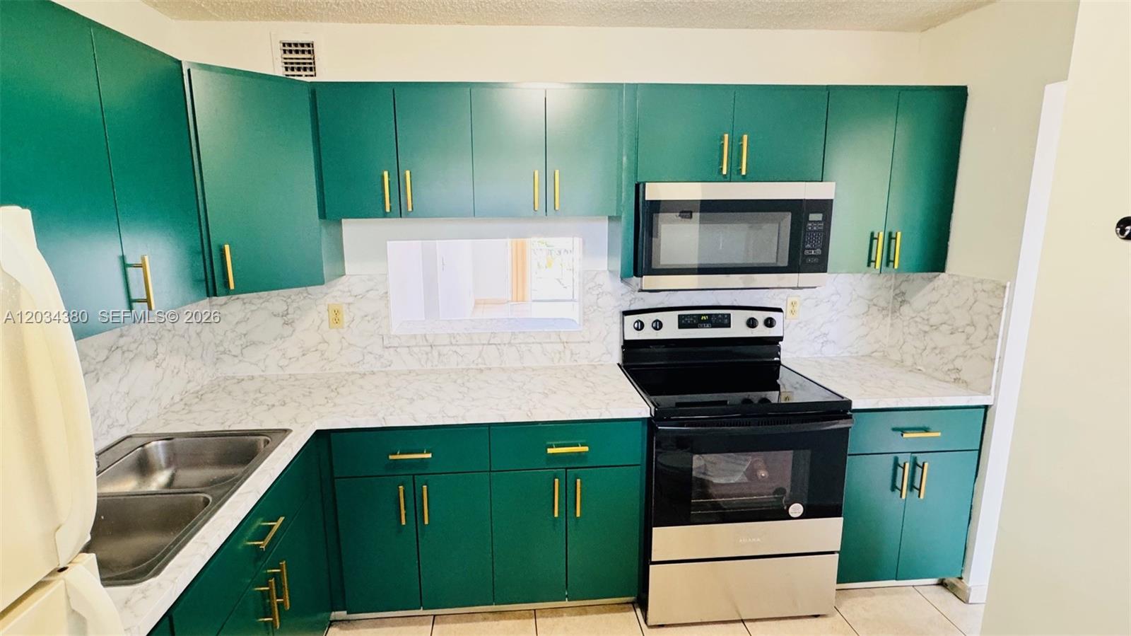 A kitchen features green cabinets, gold hardware, a marble-patterned countertop, and stainless steel appliances — 1480 W 46th St # 322, Hialeah FL 33012, HIALEAH, FL
