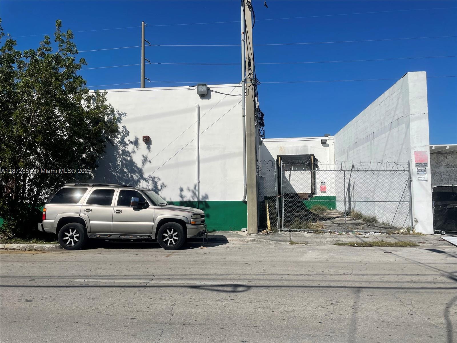 A silver SUV is parked in front of a white industrial building with a fenced loading dock — 1395 NW 22nd St, Miami FL 33142, MIAMI, FL