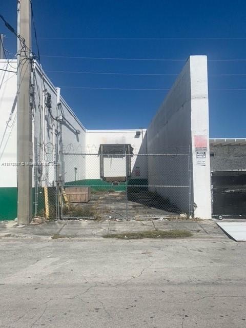 An exterior view shows a fenced-in loading dock area between two white industrial building walls — 1395 NW 22nd St, Miami FL 33142, MIAMI, FL