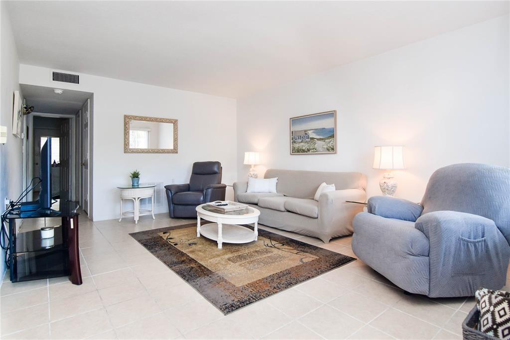 A living room features tile flooring, a beige sofa, two armchairs, and a coffee table — 8325 112TH STREET UNIT 109, SEMINOLE, FL