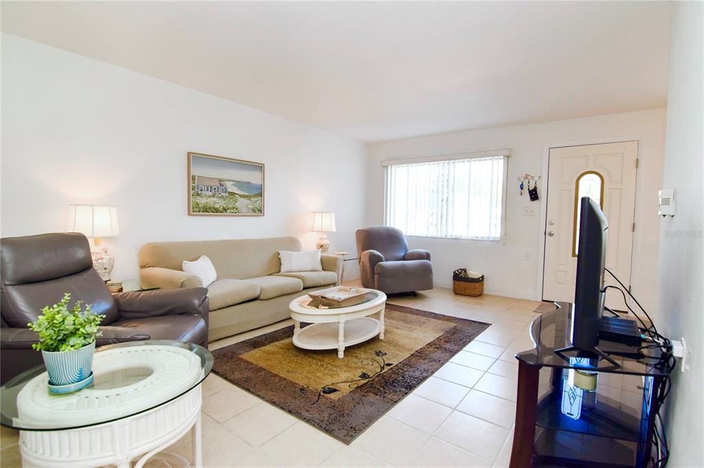 A living room features a beige sofa, two armchairs, a coffee table, and tile flooring — 8325 112TH STREET UNIT 109, SEMINOLE, FL