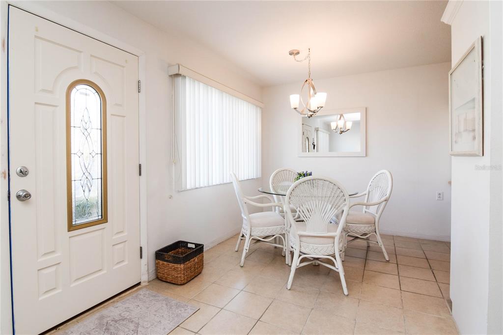 A dining area features a glass-topped table, white wicker chairs, tile flooring, and a chandelier — 8325 112TH STREET UNIT 109, SEMINOLE, FL