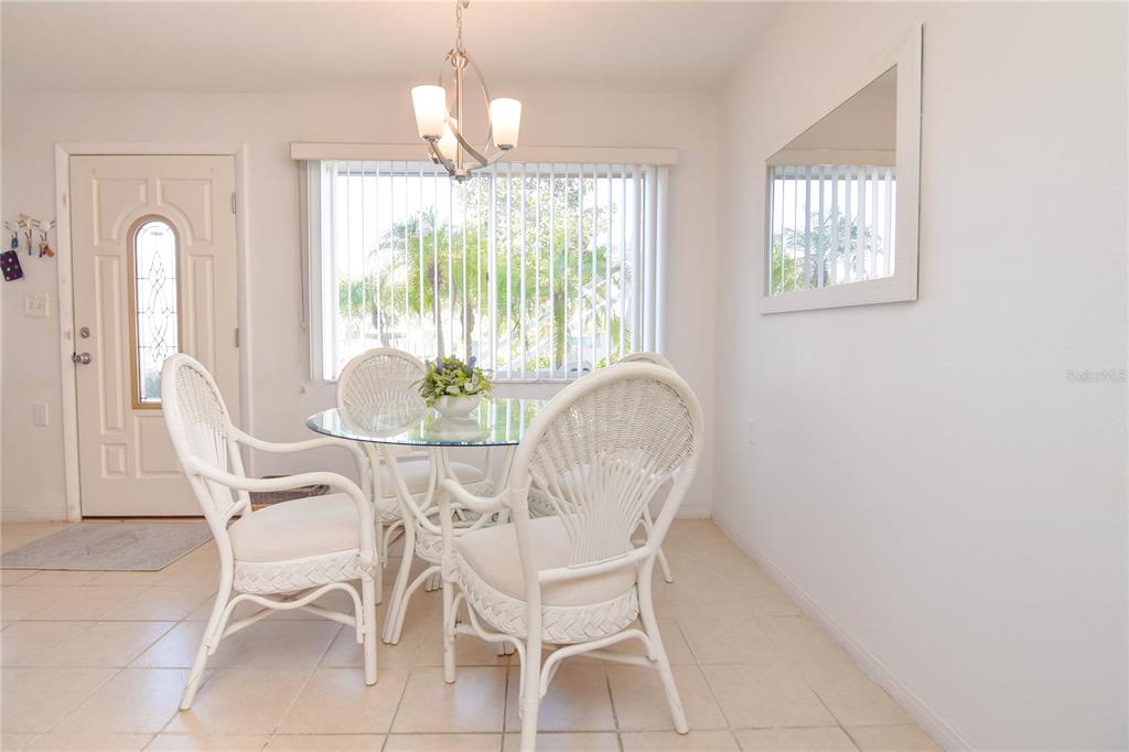 A dining area features a glass-topped table, four white wicker chairs, and a chandelier — 8325 112TH STREET UNIT 109, SEMINOLE, FL