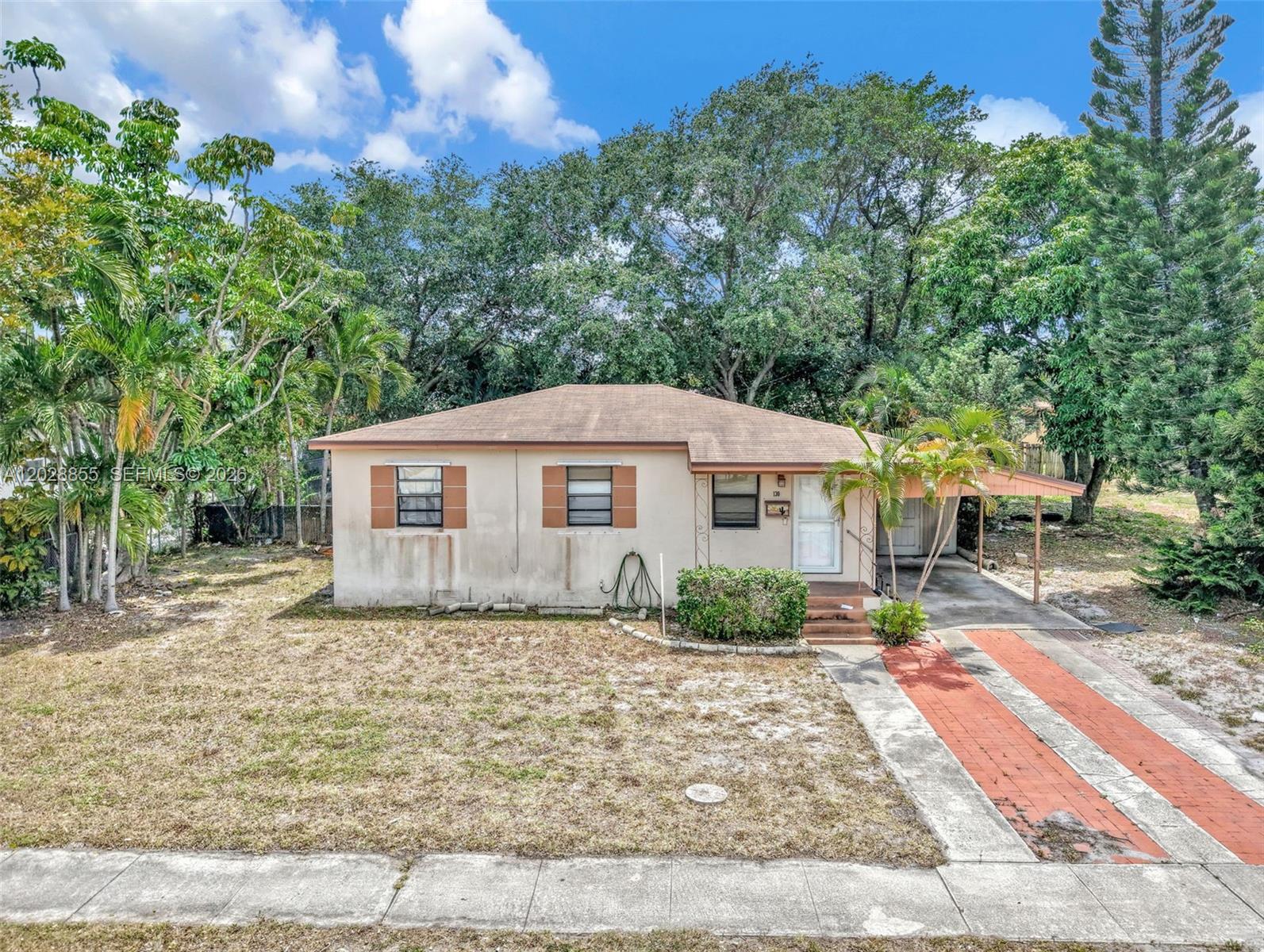 A single-story house with a tan exterior, brown shutters, and a brick-paved driveway — 130 NE 171st Ter, Miami FL 33162, MIAMI, FL