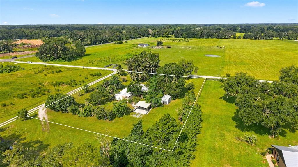 An aerial view shows a house and outbuildings on a large, fenced rural property — 13637 CR 737, WEBSTER, FL