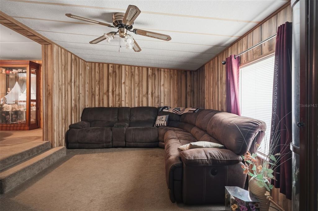 A living room features wood-paneled walls, a large brown sectional sofa, and a ceiling fan — 13637 CR 737, WEBSTER, FL