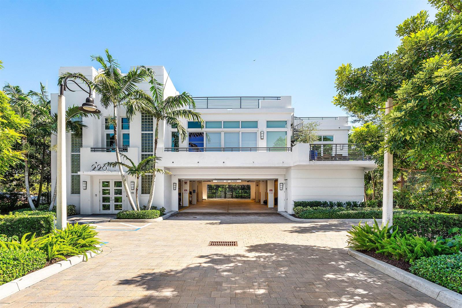 A white two-story building features a ground-level parking garage, a balcony, and palm trees — 226 Palm Court, Delray Beach FL 33444, DELRAY BEACH, FL