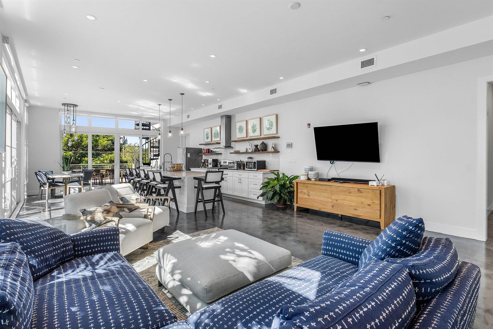 An open-concept living and kitchen area features concrete floors, white cabinetry, and a blue sofa — 226 Palm Court, Delray Beach FL 33444, DELRAY BEACH, FL