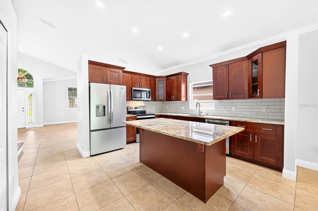 A kitchen with dark wood cabinets, granite countertops, stainless steel appliances, and tile flooring — 403 CAREY WAY, ORLANDO, FL