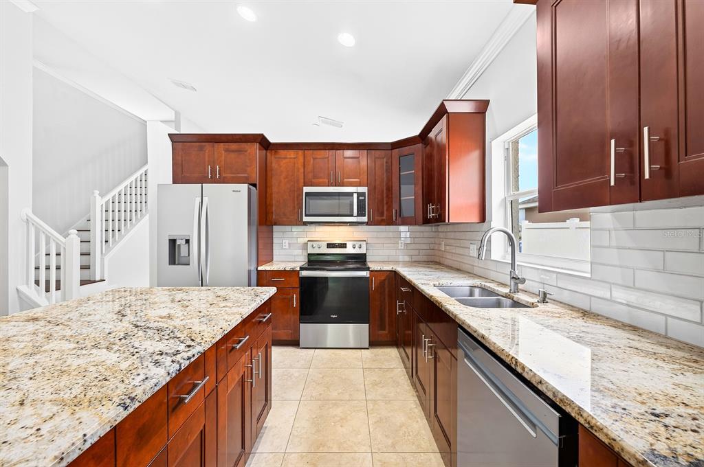A kitchen with dark wood cabinets, granite countertops, stainless steel appliances, and tile flooring — 403 CAREY WAY, ORLANDO, FL