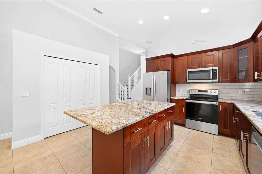 A kitchen features dark wood cabinets, granite countertops, a central island, and stainless steel appliances — 403 CAREY WAY, ORLANDO, FL
