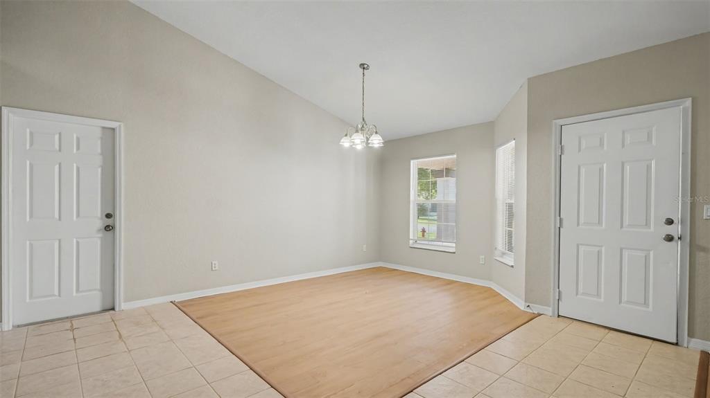 A dining area features light-colored walls, a vaulted ceiling, a chandelier, and mixed flooring — 5427 SW 87TH PLACE, OCALA, FL
