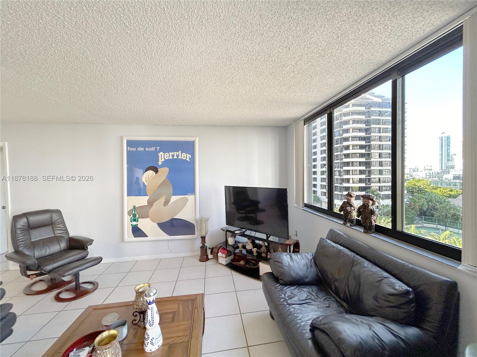 A living room features white tile floors, a leather sofa, a recliner, and city views — 540 Brickell Key Dr # 811, Miami FL 33131, MIAMI, FL