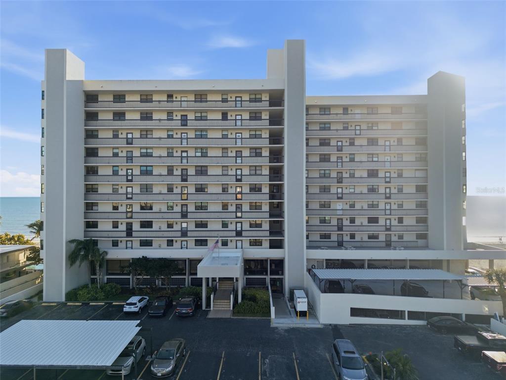 An exterior view of a multi-story apartment building with a parking lot in front — 15462 GULF BOULEVARD UNIT 406, MADEIRA BEACH, FL