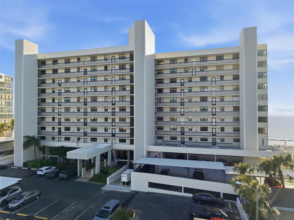 An exterior view of a multi-story apartment building with balconies and a parking lot — 15462 GULF BOULEVARD UNIT 406, MADEIRA BEACH, FL