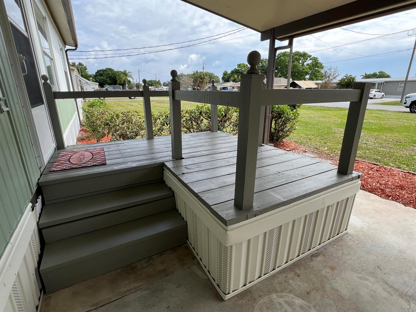 A gray wooden porch with steps and railings sits outside a mobile home — 2027 SE 27th Street, Okeechobee FL 34974, OKEECHOBEE, FL