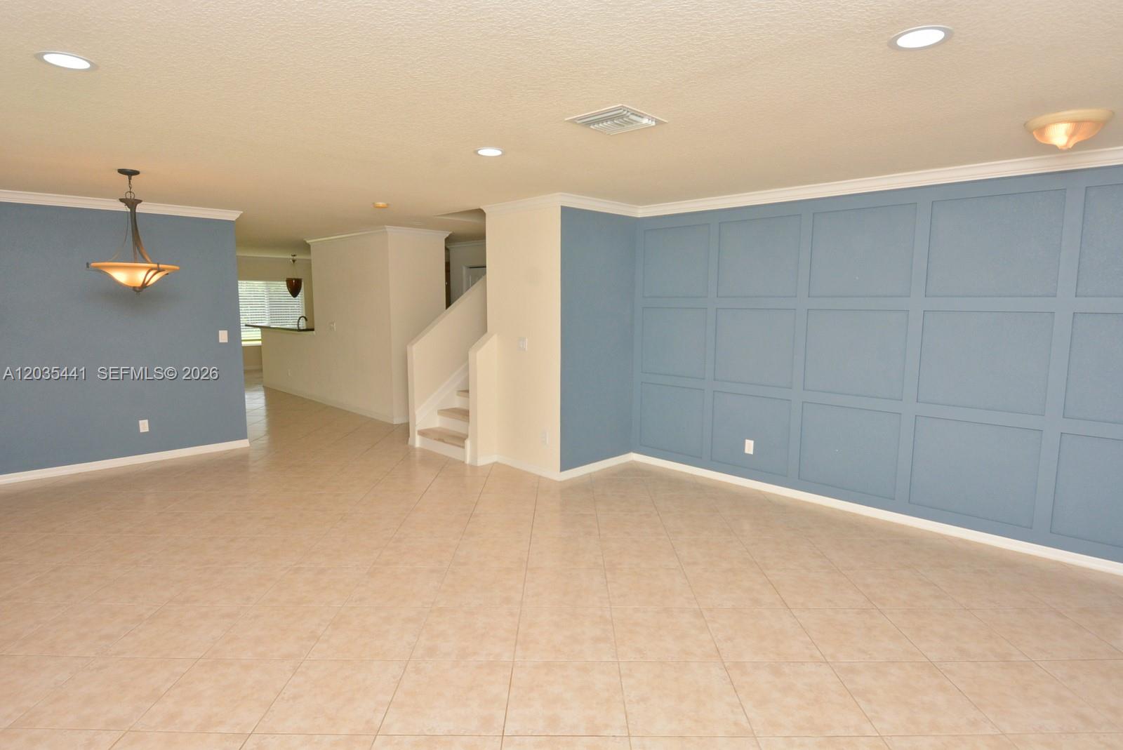An empty room features blue paneled walls, tile flooring, recessed lighting, and a staircase — 4648 56th Ln, Vero Beach FL 32967, VERO BEACH, FL
