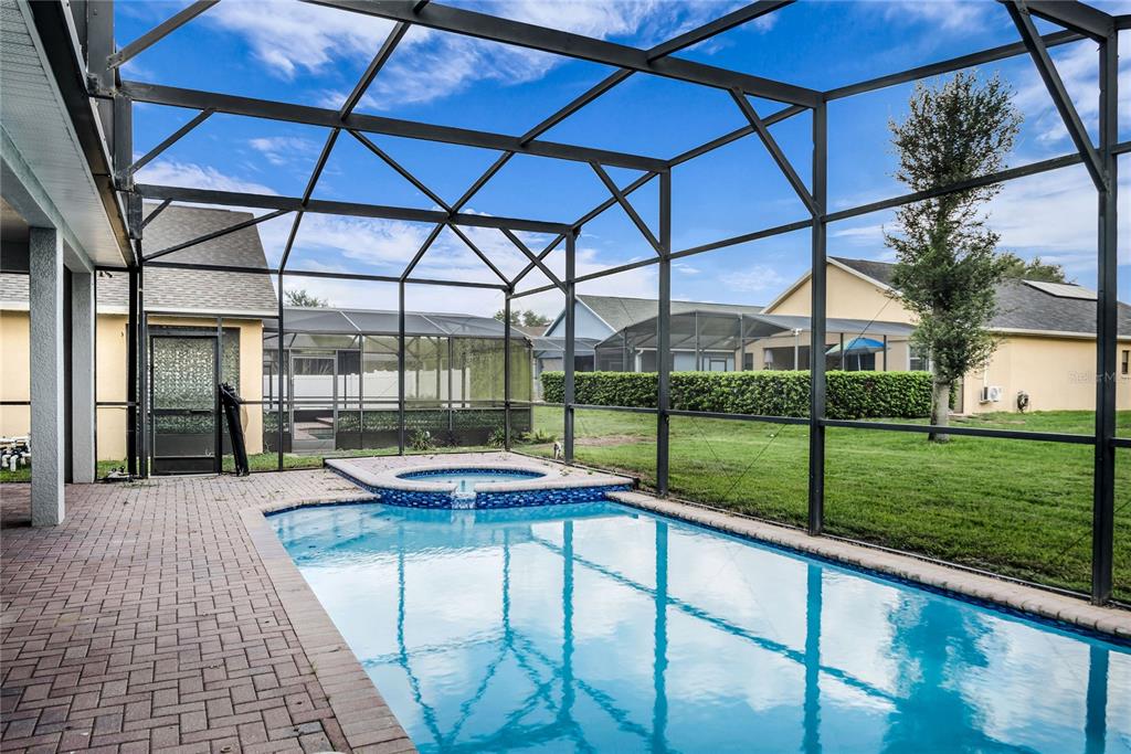 A swimming pool and spa are enclosed within a screened lanai on a paved patio — 563 LAKE DAVENPORT CIRCLE, DAVENPORT, FL