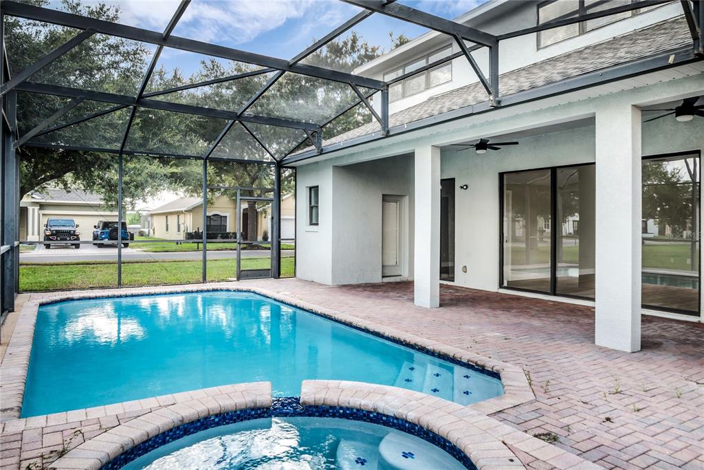 A screened-in patio features a swimming pool, a spa, and a brick paver deck — 563 LAKE DAVENPORT CIRCLE, DAVENPORT, FL