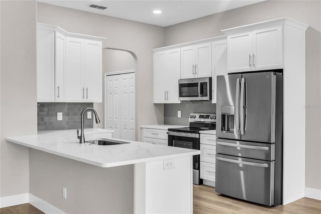 A modern kitchen with white cabinets, stainless steel appliances, and a white quartz island countertop — 563 LAKE DAVENPORT CIRCLE, DAVENPORT, FL