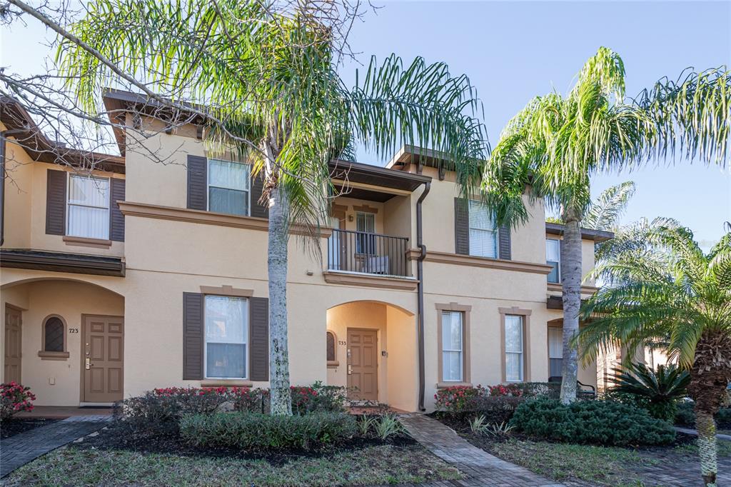 The exterior of a two-story stucco townhouse features palm trees and a small balcony — 733 CALABRIA AVENUE, DAVENPORT, FL