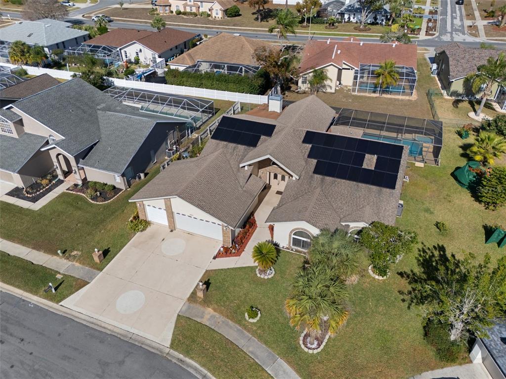 An aerial view shows a suburban house with solar panels on the roof and a pool — 10421 TEMPLEWOOD COURT, SPRING HILL, FL