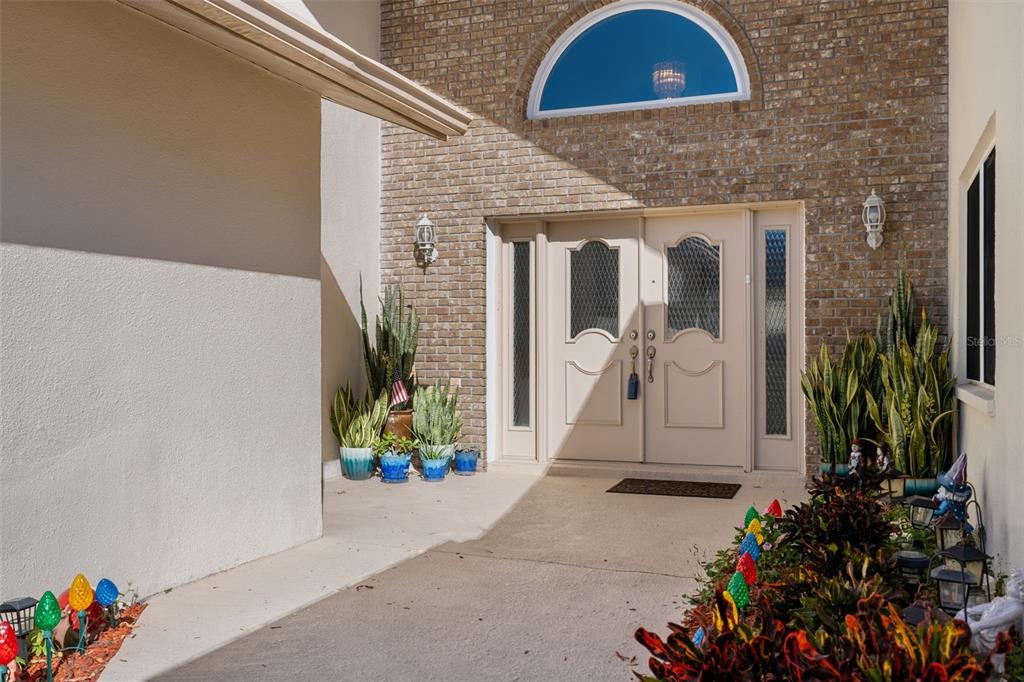 The exterior entrance features a brick facade, double front doors, and a semi-circular window — 10421 TEMPLEWOOD COURT, SPRING HILL, FL