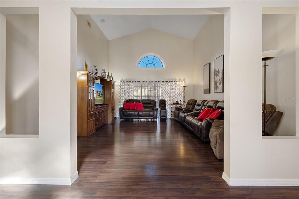 A living room with dark wood flooring, vaulted ceilings, and brown leather furniture — 10421 TEMPLEWOOD COURT, SPRING HILL, FL