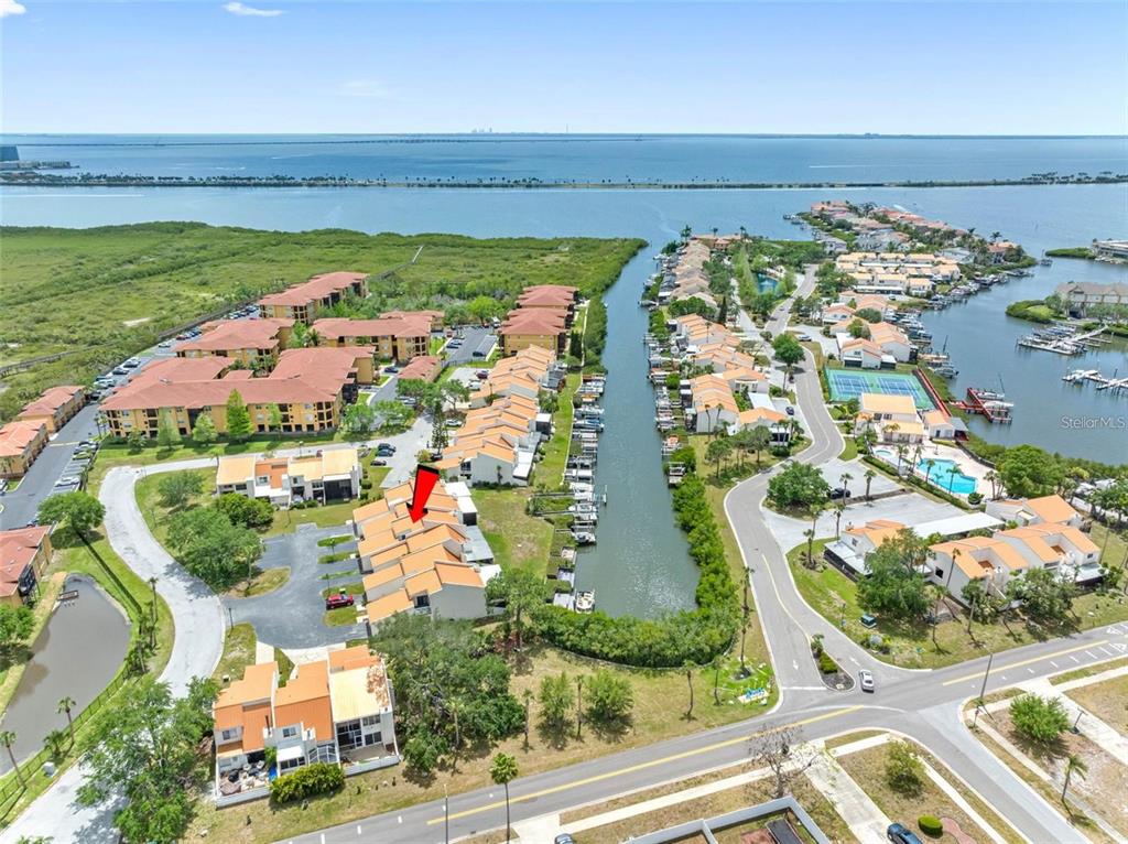 An aerial view shows a residential complex with townhomes, a canal, and a nearby bay — 4306 SUNRAY COURT, TAMPA, FL
