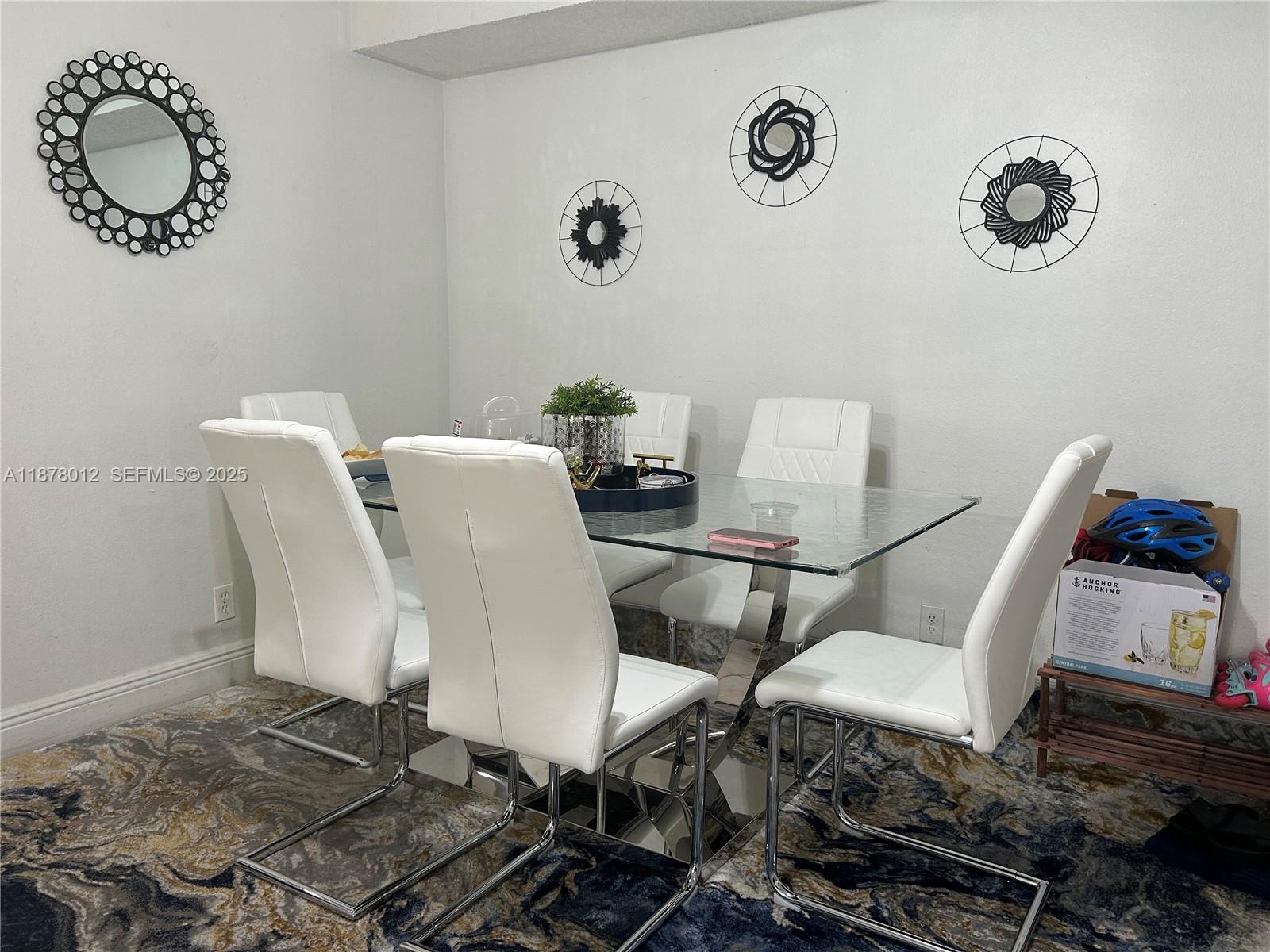 A dining room features a glass-topped table, white chairs, and decorative wall mirrors — 17901 NW 68th Ave # T101, Hialeah FL 33015, HIALEAH, FL