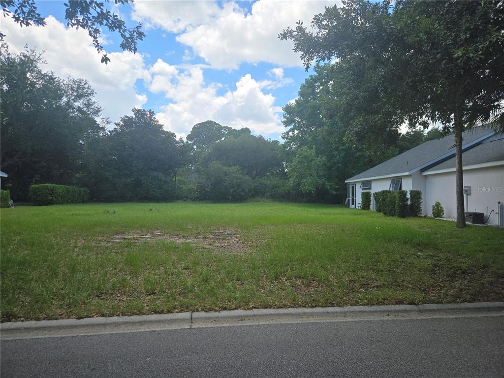 A vacant, grassy residential lot sits between a paved street and a neighboring house — 13 SAINT ANDREWS COURT, PALM COAST, FL