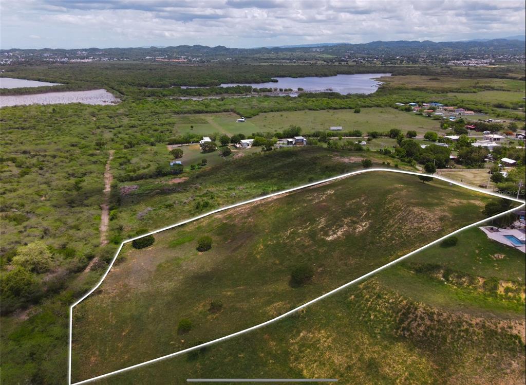 An aerial view shows a large, grassy, sloped plot of land outlined in white — Carr 301 km 3.2 MONTELCARLO STATE, CABO ROJO, PR