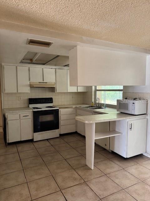 A kitchen with white cabinets, tile flooring, a black stove, and a peninsula counter — 8811 GOSHEN LANE, PORT RICHEY, FL