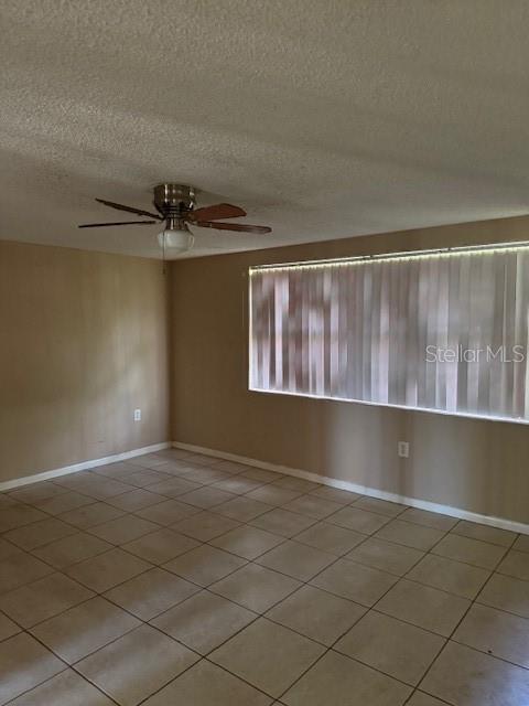 An empty room features beige walls, a tiled floor, and a ceiling fan — 8811 GOSHEN LANE, PORT RICHEY, FL