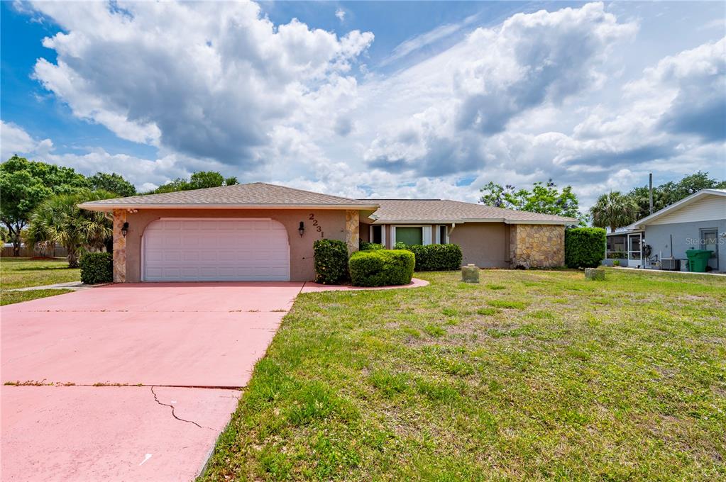A single-story house with a pink driveway, a two-car garage, and stone accents — 22317 LAIKA AVENUE, PORT CHARLOTTE, FL