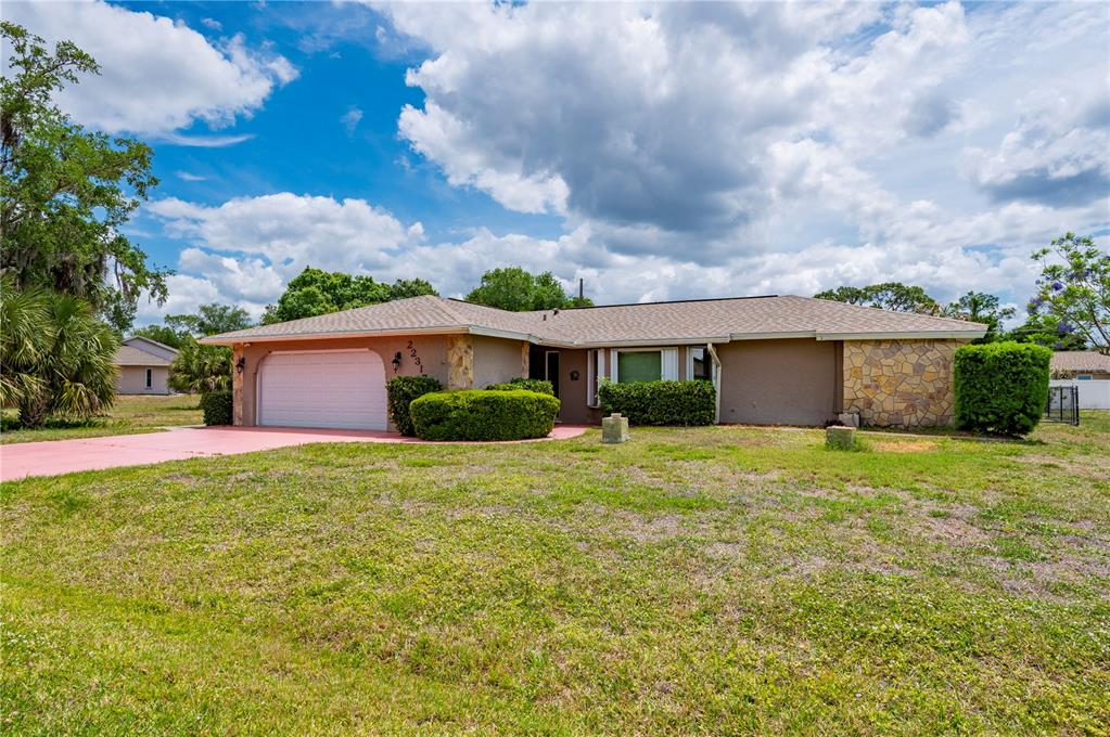 A single-story house with a garage, stone accents, and a large front lawn — 22317 LAIKA AVENUE, PORT CHARLOTTE, FL