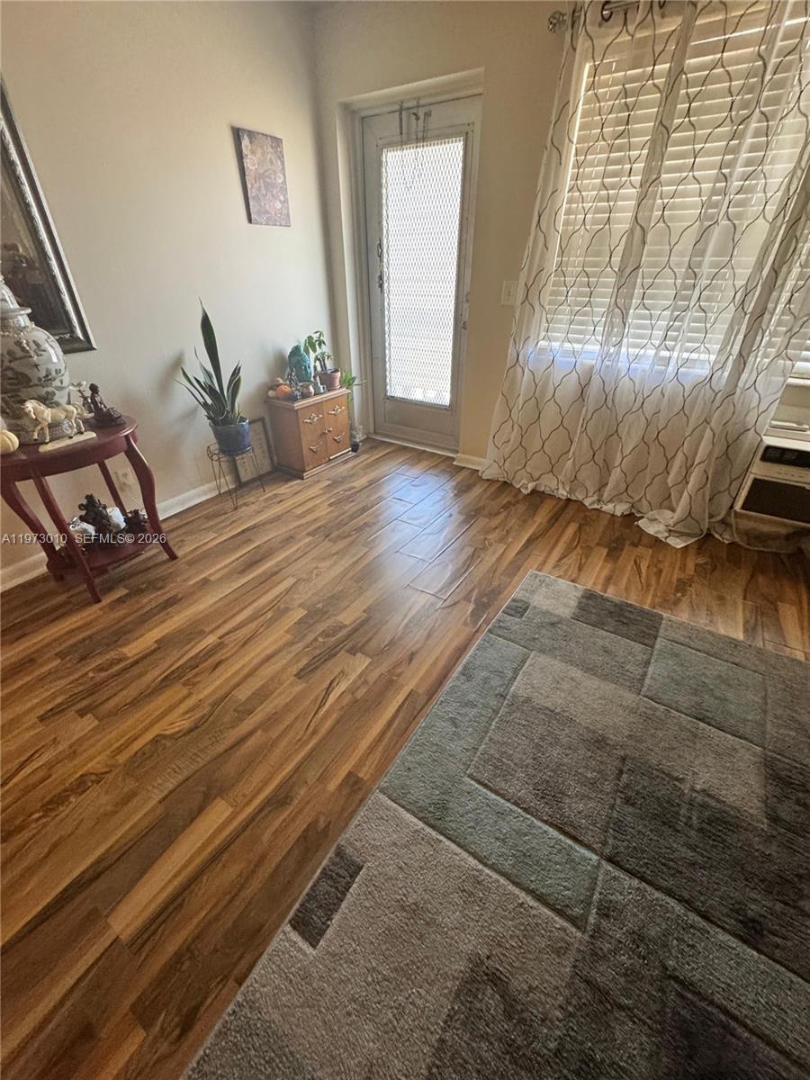 A room with wood-look flooring, a glass door, and a large window with curtains — 142 Northampton G # 142, West Palm Beach FL 33417, WEST PALM BEACH, FL
