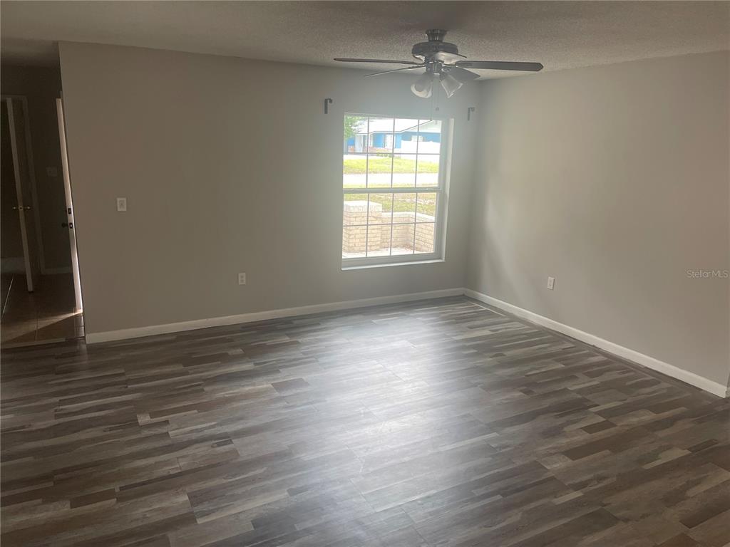 A room with gray walls, a ceiling fan, and wood-look flooring features a single window — 906 ESSEX ROAD, BRANDON, FL