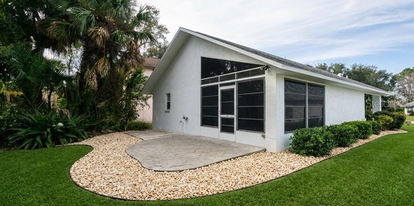 The exterior of a white house features a screened-in porch and a stone patio — 4613 BARNACLE DRIVE, PORT ORANGE, FL