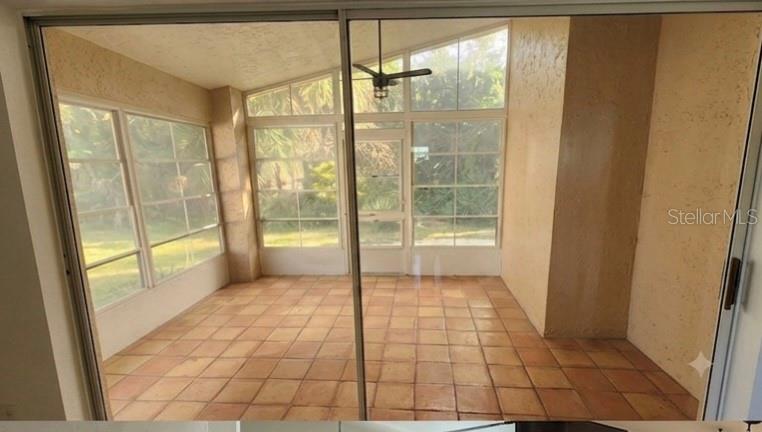 A sunroom features terracotta tile flooring, large windows, and a ceiling fan — 4613 BARNACLE DRIVE, PORT ORANGE, FL