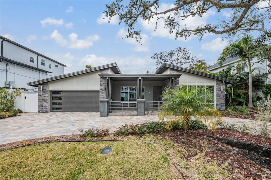 A modern single-story house with a stone-accented facade, a paved driveway, and a covered entryway — 4909 W DRYAD STREET, TAMPA, FL