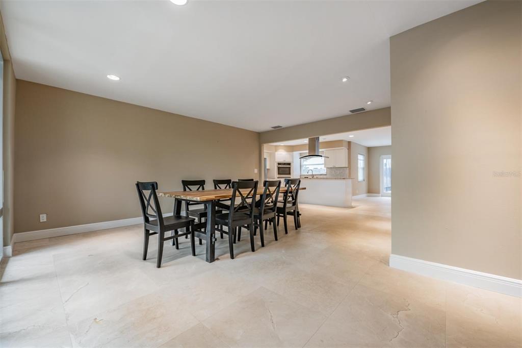 A dining area with a wooden table and black chairs sits on light tile flooring — 4909 W DRYAD STREET, TAMPA, FL
