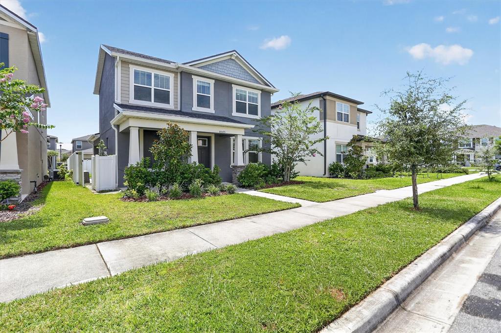 A two-story gray house with a front porch and a green lawn under a blue sky — 8565 LAMPPOST LANE, ORLANDO, FL