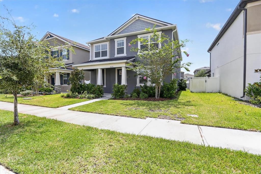 A two-story gray house with a front porch and a green lawn under a blue sky — 8565 LAMPPOST LANE, ORLANDO, FL