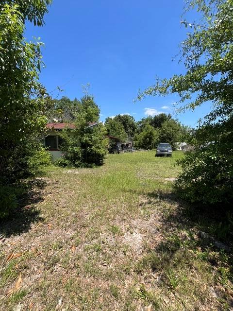 A small house sits on a grassy lot with trees and a parked car — 727 S Washington Avenue, FL 32703, FL