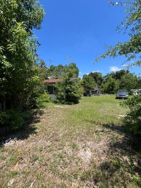 A small house sits in a grassy yard surrounded by trees under a clear sky — 727 S Washington Avenue, FL 32703, FL